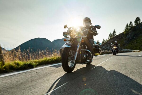 Motorcycle Insurance - Motorcycle Driver Riding Along a Scenic Highway at Dusk With Mountains in the Distance