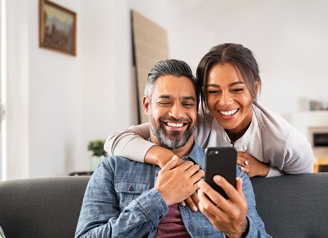 Read Our Reviews - Happy Couple Using Smartphone at Home